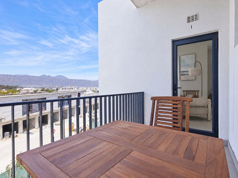 A private balcony featuring a metal balustrade and views of the surrounding area, accessible through a glass door.