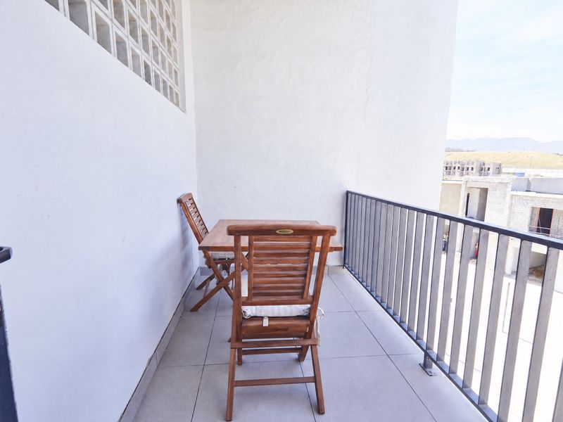 A private balcony featuring tiled flooring, a metal safety balustrade, and a decorative glass block window section.
