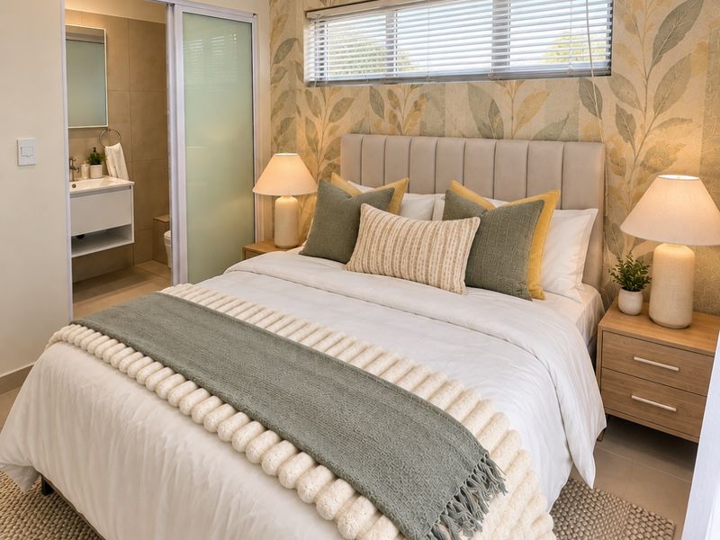 A well-appointed bedroom featuring patterned wallpaper, tiled flooring, and an integrated en-suite bathroom with modern fixtures.