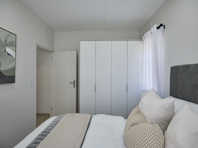 A well-maintained bedroom featuring a modern built-in wardrobe, neutral wall finishes, and a clean, contemporary aesthetic.