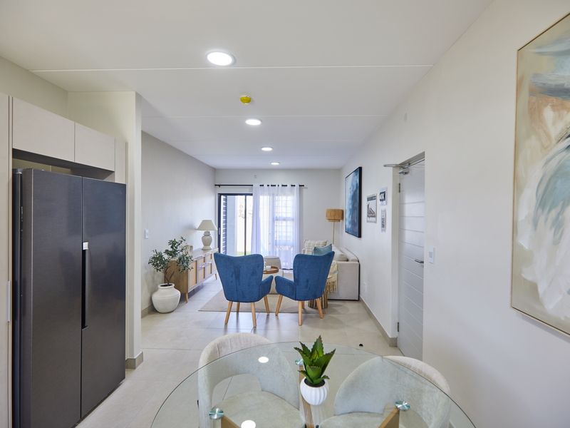 A bright and modern open-plan living area featuring tiled floors, recessed lighting, and a sliding glass door leading to an outdoor space.