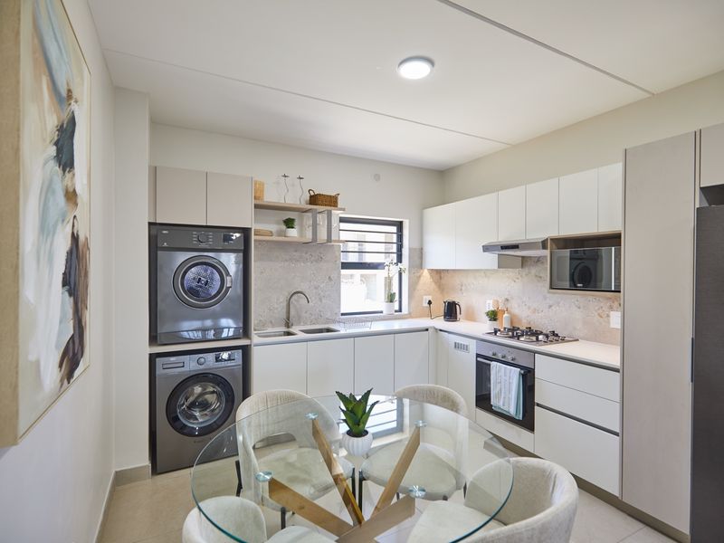 Modern kitchen featuring sleek white cabinetry, stone-look backsplash, integrated laundry appliances, and high-quality built-in cooking fixtures.