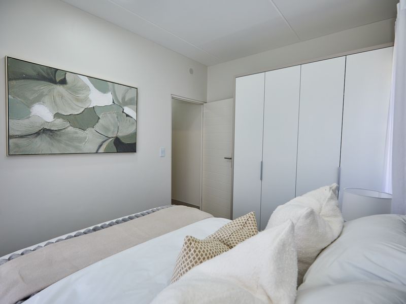 A well-maintained bedroom featuring neutral walls, built-in cupboards, and a clean, modern aesthetic.
