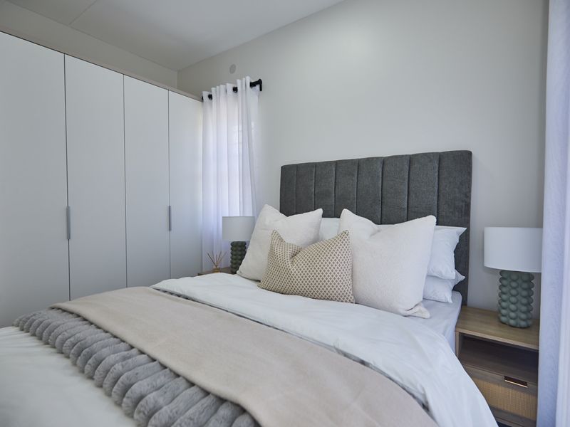 A well-maintained bedroom featuring a large built-in wardrobe and neutral finishes, creating a clean and comfortable living space.