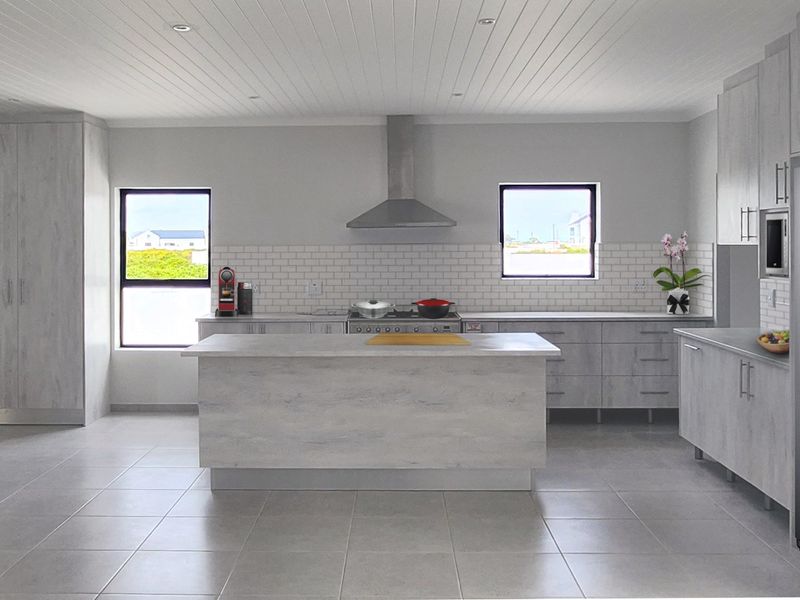 Modern kitchen featuring light wood-grain cabinetry, a central island, subway tile backsplash, stainless steel appliances, and recessed lighting under a tongue and groove ceiling.