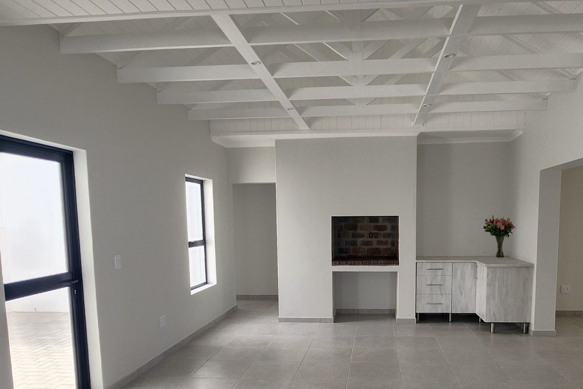 Bright and spacious living area featuring a high exposed beam ceiling, tiled floors, and a built-in fireplace with adjacent cabinetry.