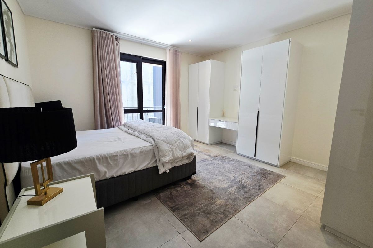 A well-maintained bedroom featuring neutral tiled flooring, built-in white cabinetry, and a sliding glass door providing access to an outdoor area.