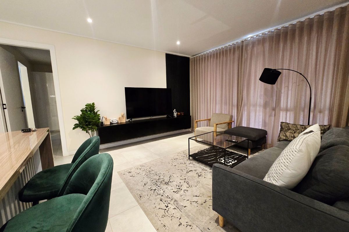 A modern, well-maintained living room featuring tiled flooring, recessed lighting, and a sleek built-in media console with decorative slatted wall paneling.