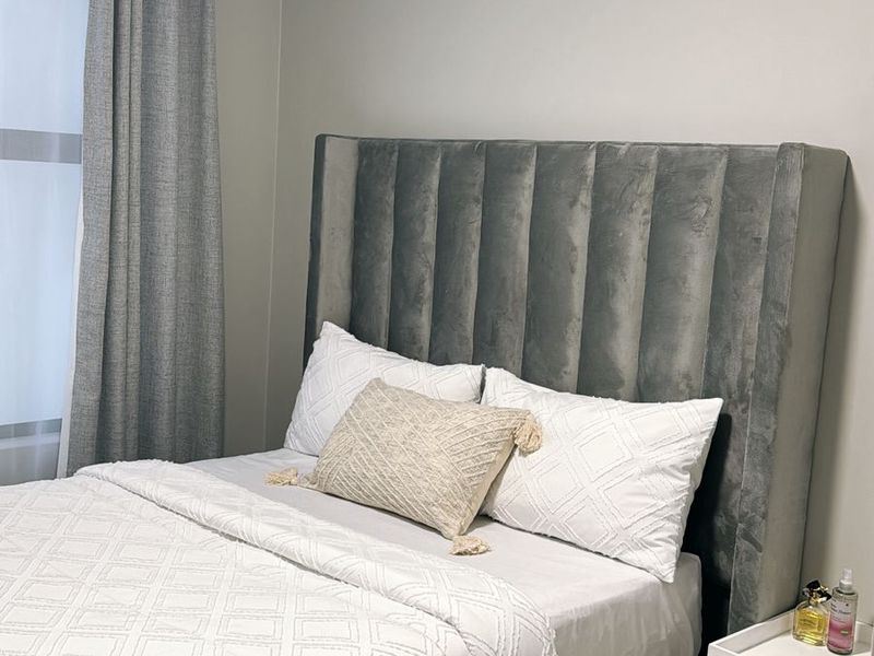 A well-maintained bedroom featuring neutral wall tones, tiled flooring, and a large window allowing for natural light.
