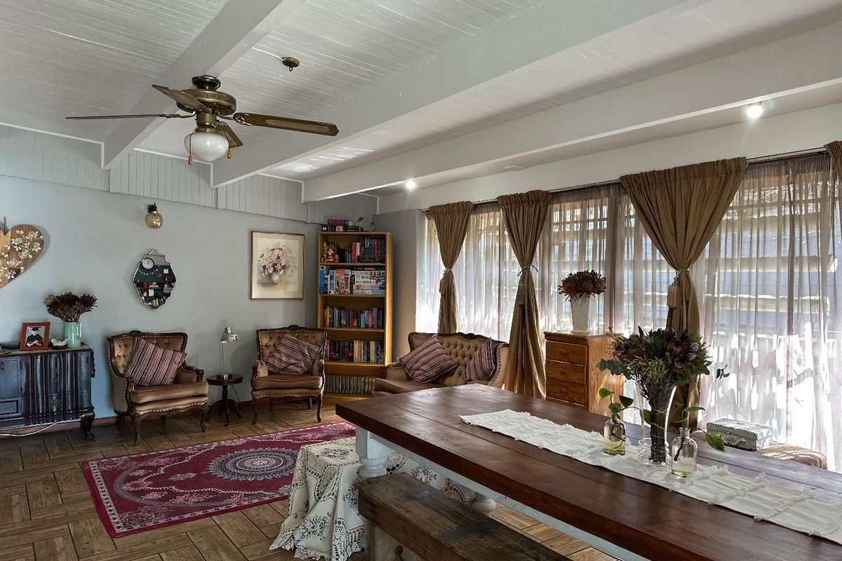 Spacious living area featuring exposed beam ceilings, a ceiling fan, and classic parquet flooring with large windows allowing for ample natural light.