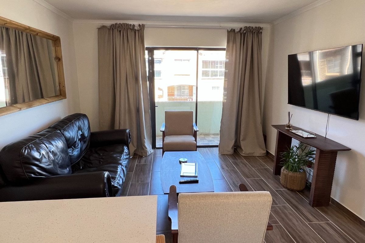 A well-maintained living room featuring modern tiled flooring and a sliding glass door that provides access to an outdoor balcony area.