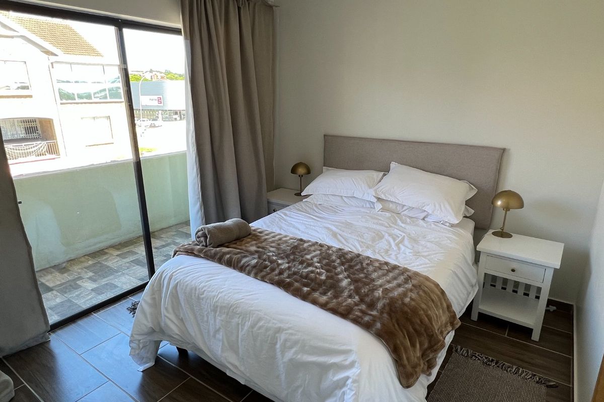 A well-maintained bedroom featuring modern tiled flooring and a large sliding glass door providing access to an outdoor balcony area.