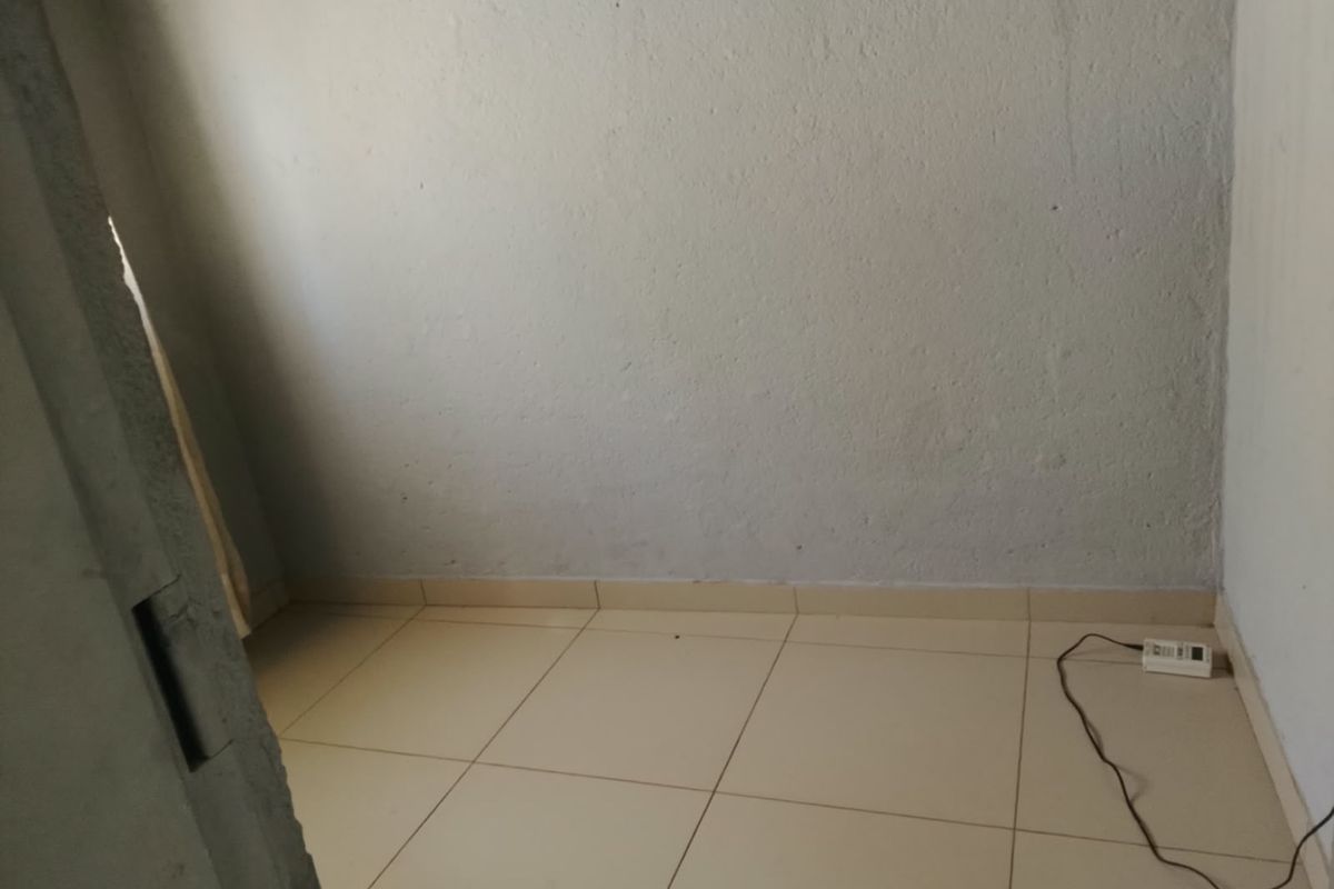 An empty bedroom featuring tiled flooring and plain walls, suitable for renovation or staging to enhance its appeal.