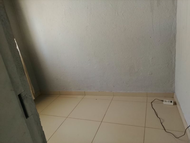 An empty bedroom featuring tiled flooring and plain walls, suitable for renovation or staging to enhance its appeal.