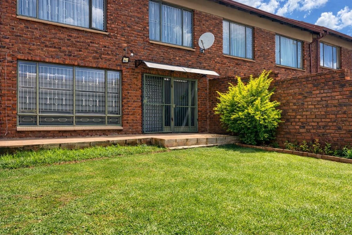 Rear view of the apartment featuring a face brick facade, a private garden, and a concrete patio area with security features.