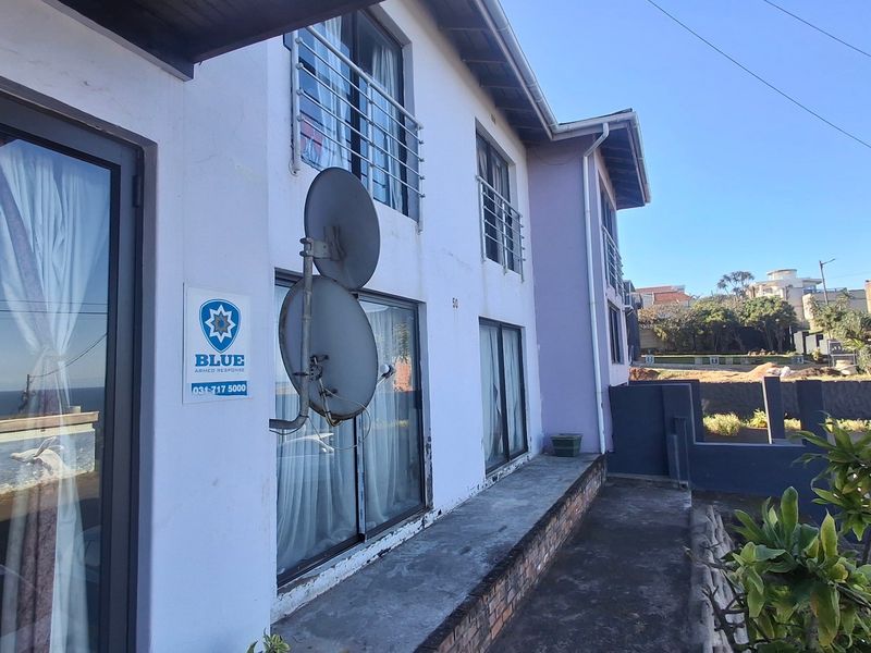 Front exterior view of a multi-story residential building featuring sliding glass doors, metal security bars, and a satellite dish installation.