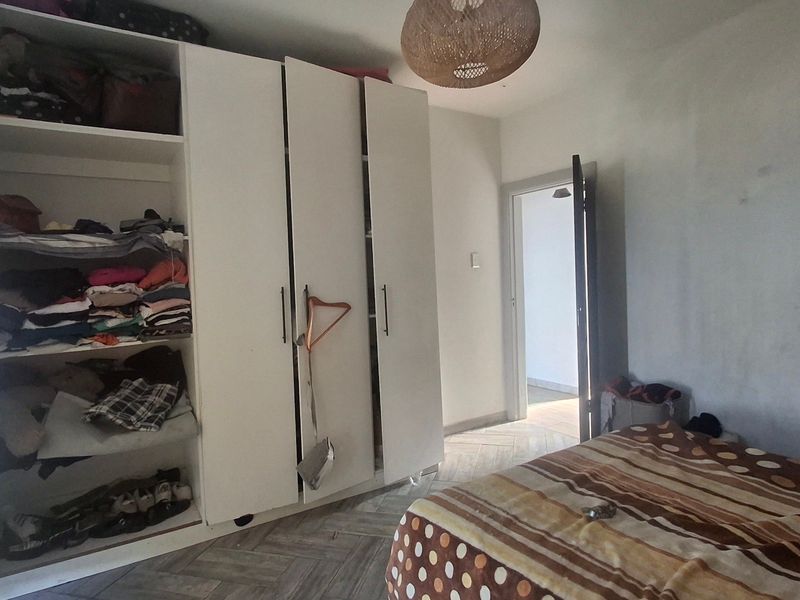 A bedroom featuring built-in wardrobes and herringbone tile flooring, requiring minor cosmetic updates to the wall finishes.
