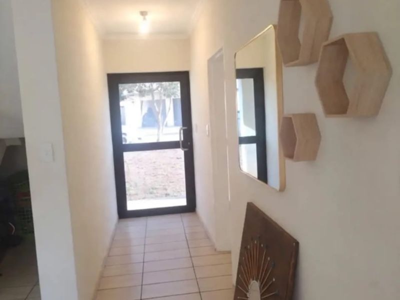 A bright entrance hallway featuring neutral tiled flooring and a glass panelled entrance door leading to the exterior.