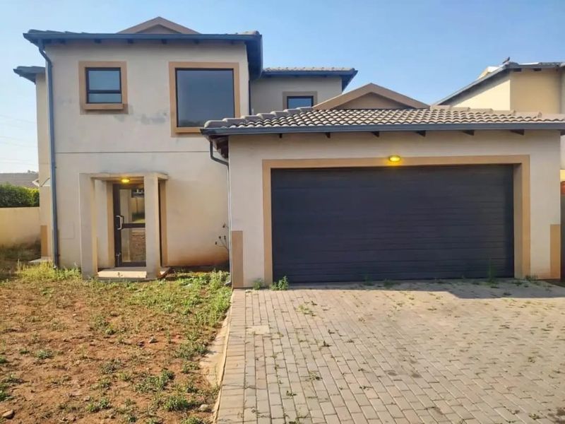 Front elevation of a two-story apartment featuring a double garage, paved driveway, and a covered entrance with a small garden area.