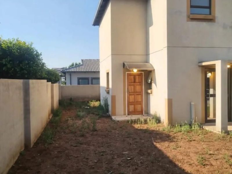 Rear view of the apartment featuring a private garden area with boundary wall and a timber entrance door.