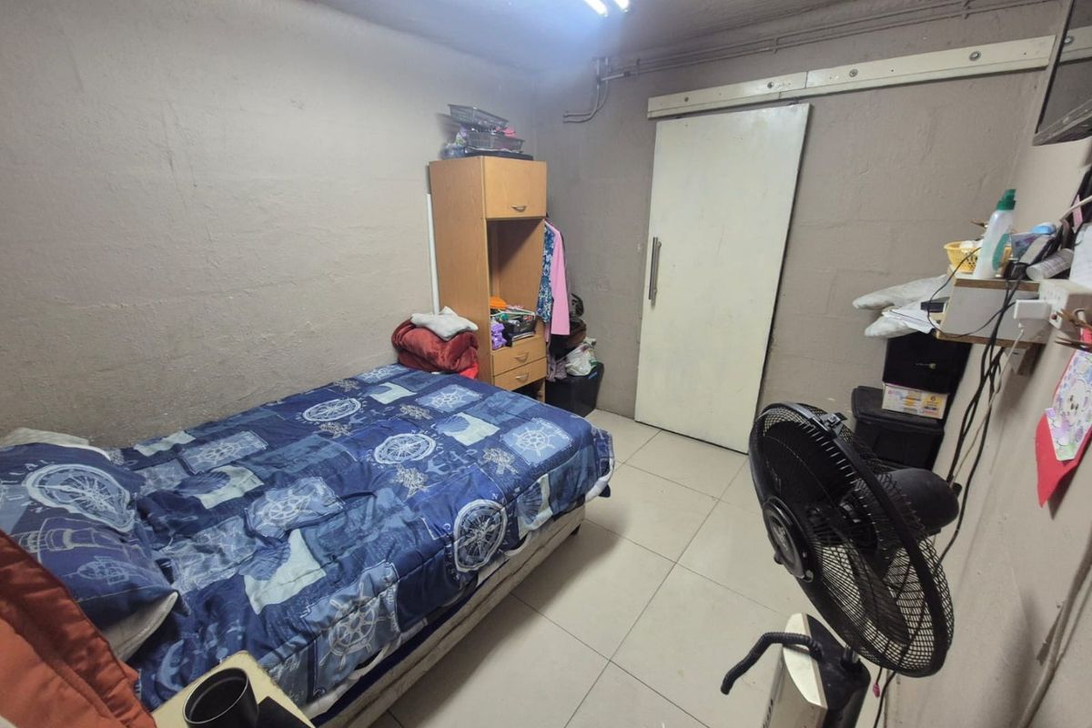 A basic bedroom featuring tiled flooring and a sliding door, currently requiring cosmetic updates to wall finishes and electrical infrastructure.
