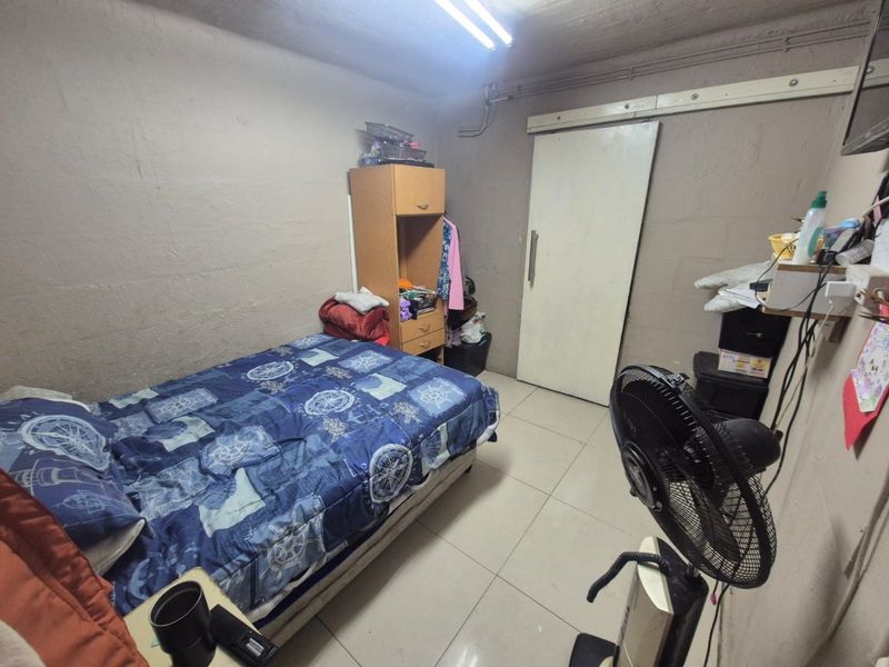 A basic bedroom featuring tiled flooring and a sliding door, currently requiring cosmetic updates to wall finishes and electrical infrastructure.