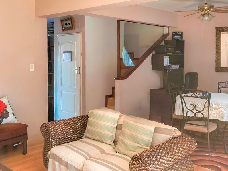 Open plan living and dining area featuring laminate flooring, a ceiling fan, and a staircase with a glass balustrade.