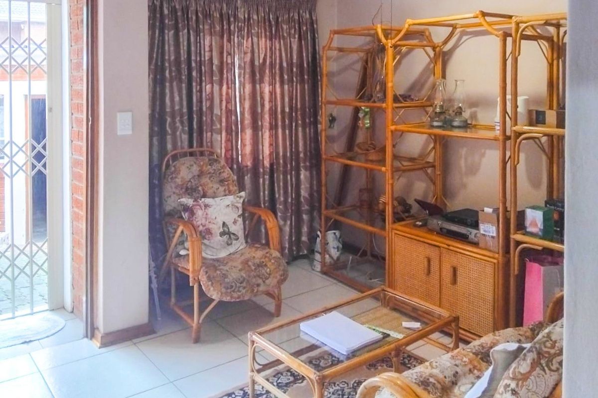 A living room area featuring tiled flooring and a sliding door with a security gate, providing access to the exterior.
