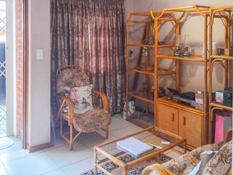A living room area featuring tiled flooring and a sliding door with a security gate, providing access to the exterior.