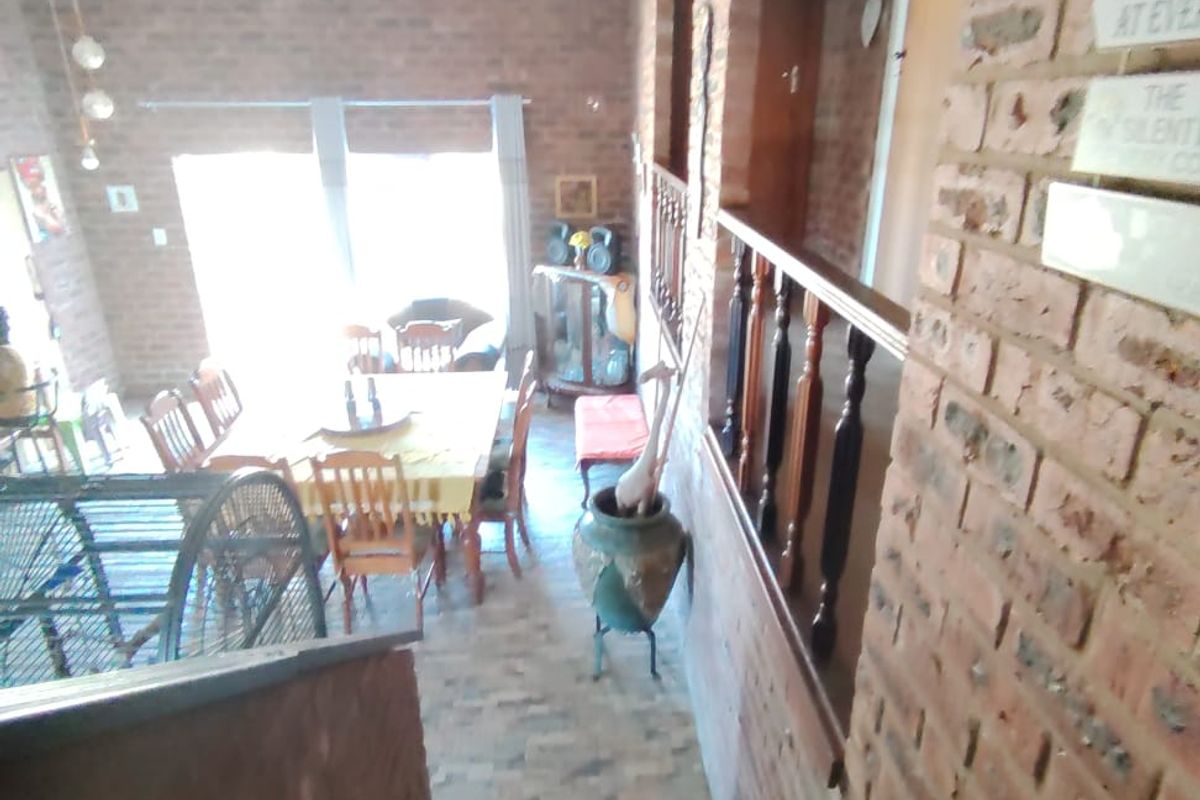 View from a staircase looking down into an open-plan living and dining area featuring exposed brick walls and a timber balustrade.