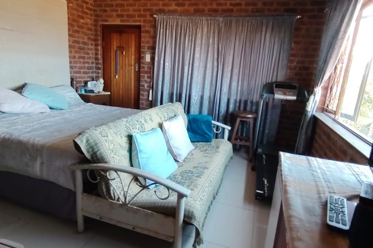 A bedroom featuring exposed brick walls and tiled flooring, offering a rustic aesthetic that could be enhanced with modern updates.