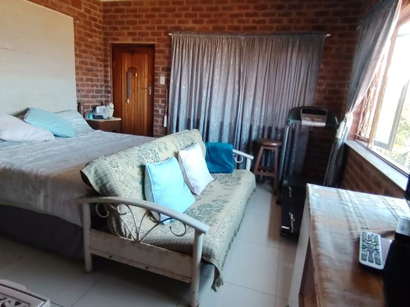 A bedroom featuring exposed brick walls and tiled flooring, offering a rustic aesthetic that could be enhanced with modern updates.
