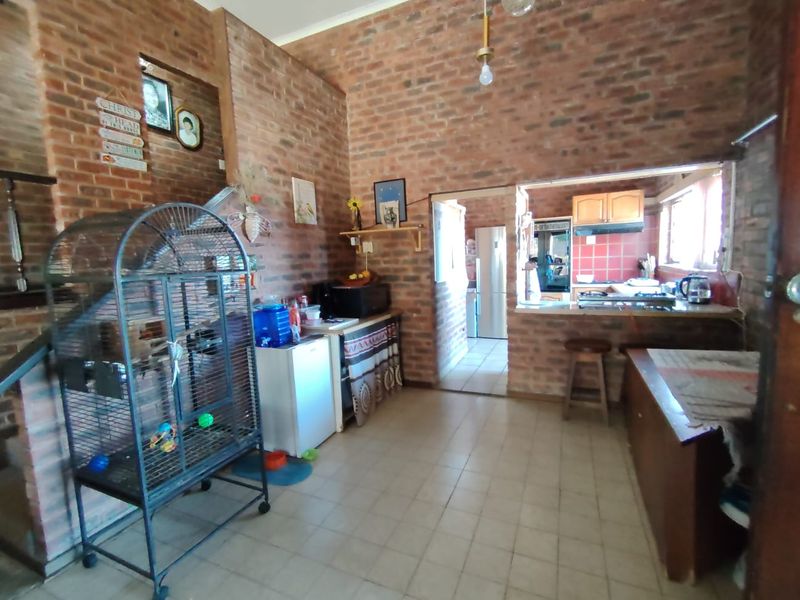 Open plan living and kitchen area featuring exposed brick walls, tiled flooring, and a breakfast bar connecting to the kitchen space.
