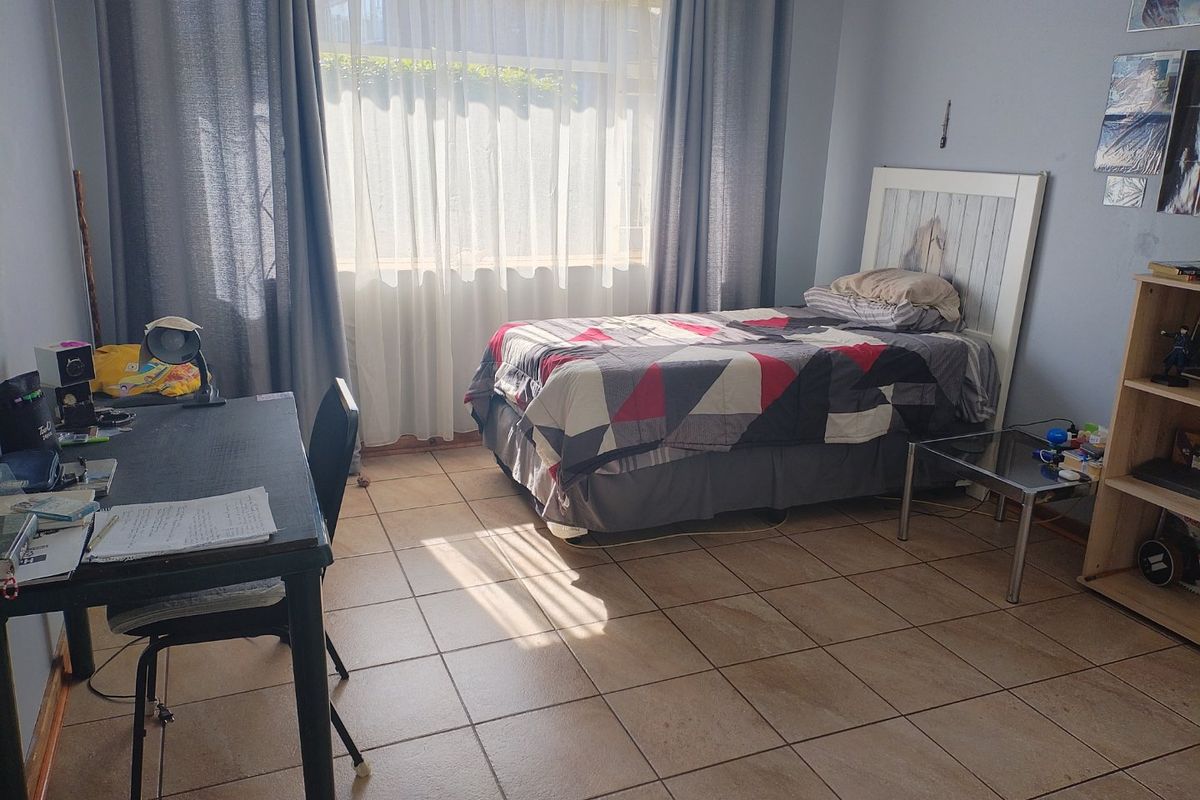 A functional bedroom featuring tiled flooring and a large window that allows for natural light.