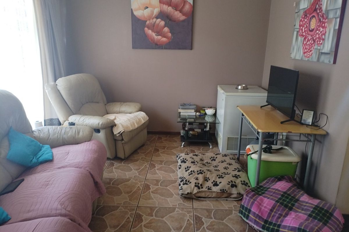 A living room area featuring tiled flooring and access to natural light through a sliding glass door.