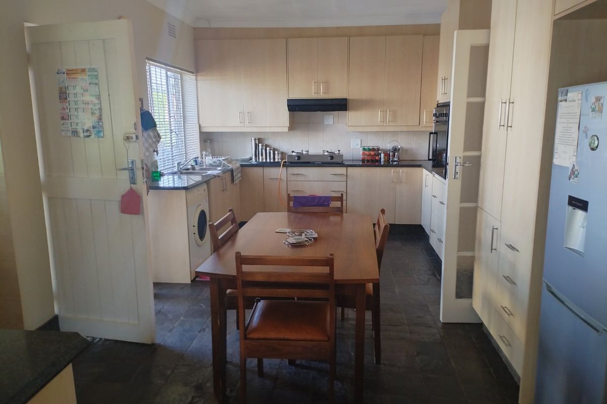 Functional kitchen featuring light wood cabinetry, dark countertops, gas hob, built-in oven, and tiled flooring with an integrated dining area.