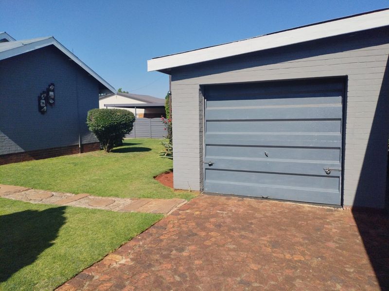 Exterior view of a detached garage with a painted brick facade, sectional door, and a paved driveway leading to the structure.