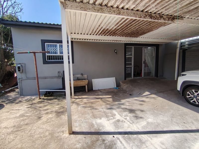 Covered outdoor patio area featuring a concrete floor, external wash basin, and security-fitted sliding door access to the main dwelling.