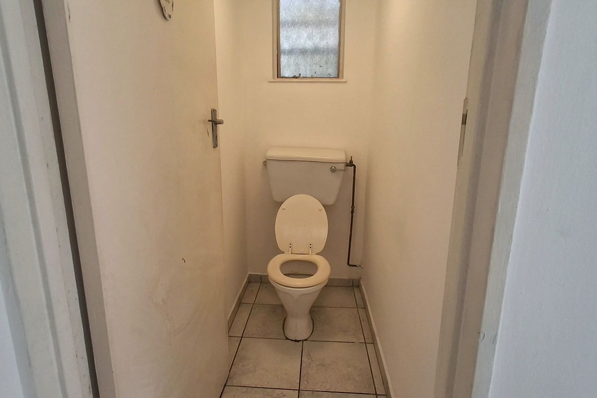 A compact, functional bathroom featuring a standard toilet, tiled flooring, and an obscured glass window for privacy.