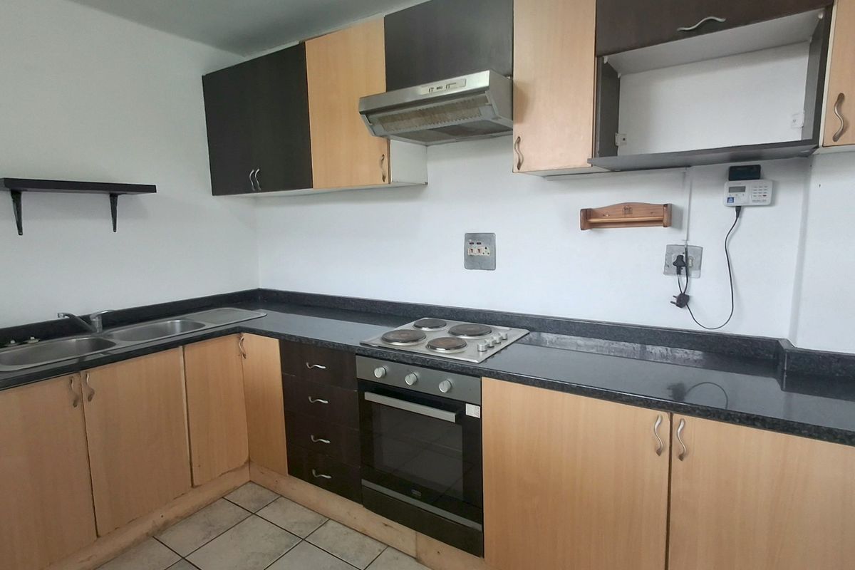 A functional kitchen featuring built-in cabinetry, dark laminate countertops, a stainless steel sink, and integrated electric cooking appliances.