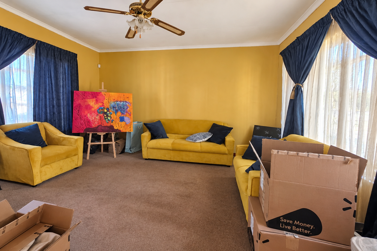 A spacious living room featuring carpeted flooring and a central ceiling fan, offering a comfortable area for relaxation.