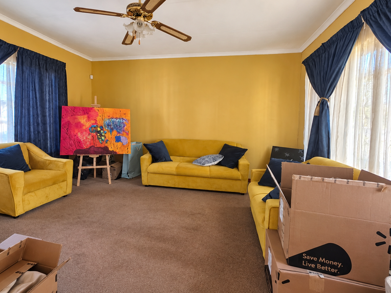 A spacious living room featuring carpeted flooring and a central ceiling fan, offering a comfortable area for relaxation.