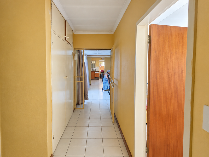 A functional hallway featuring tiled flooring and built-in storage cupboards, providing access to adjacent rooms within the home.