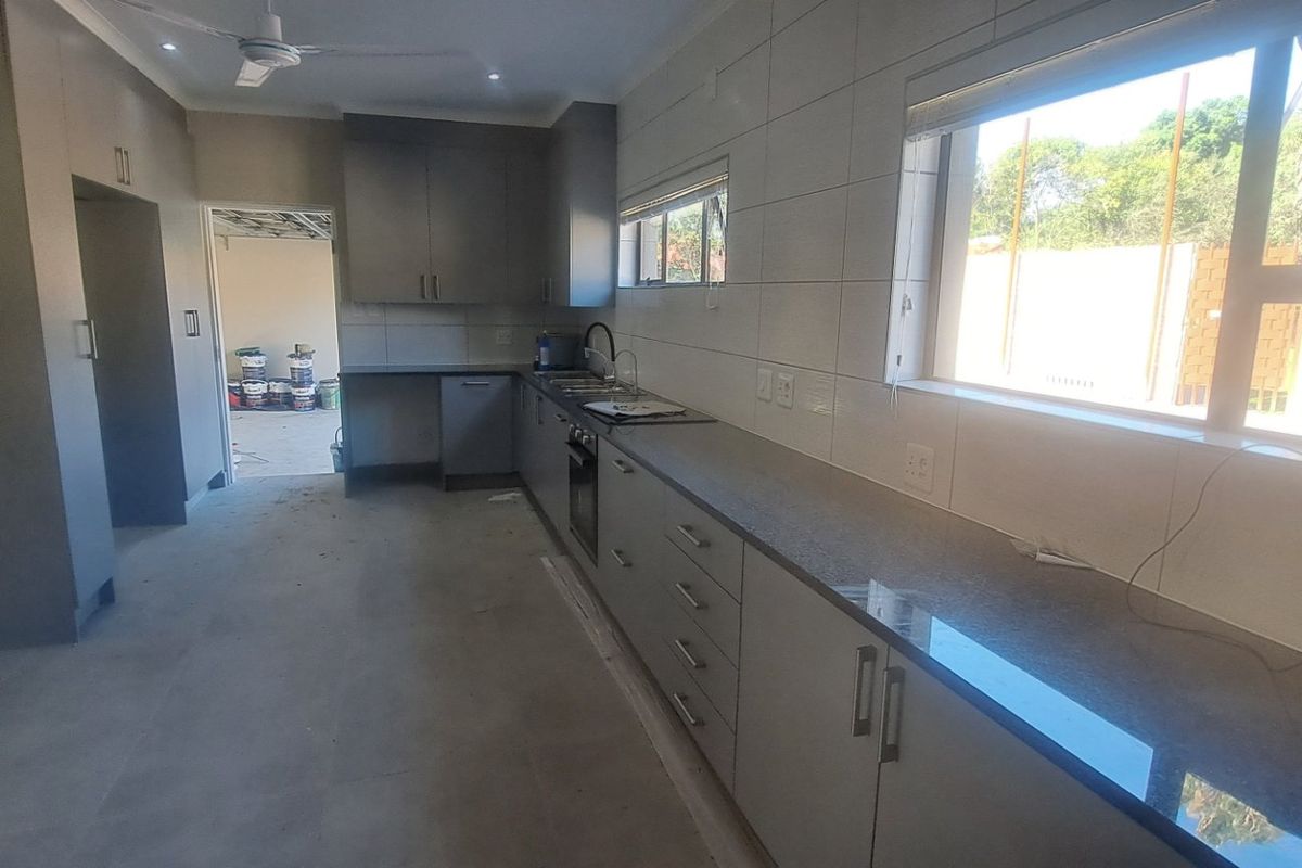 A modern, newly installed kitchen featuring grey cabinetry, stone countertops, and integrated appliances, currently in the final stages of completion.