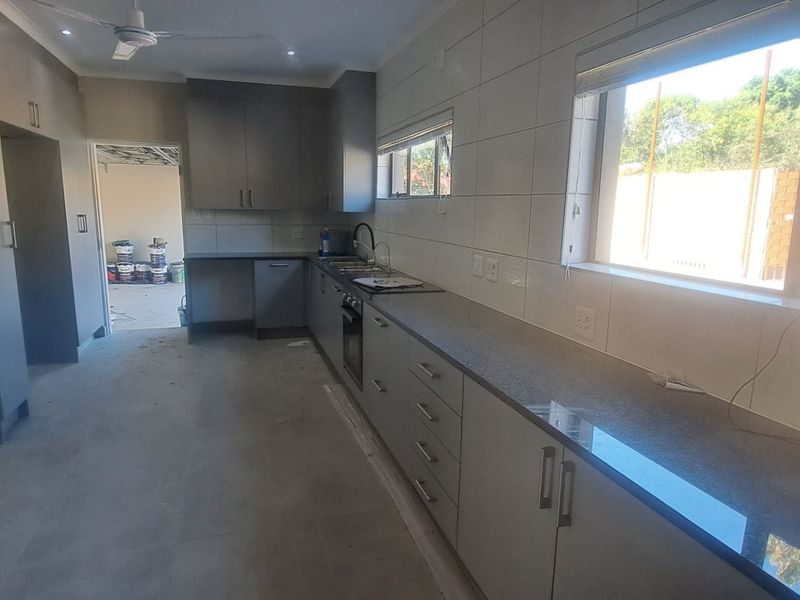 A modern, newly installed kitchen featuring grey cabinetry, stone countertops, and integrated appliances, currently in the final stages of completion.