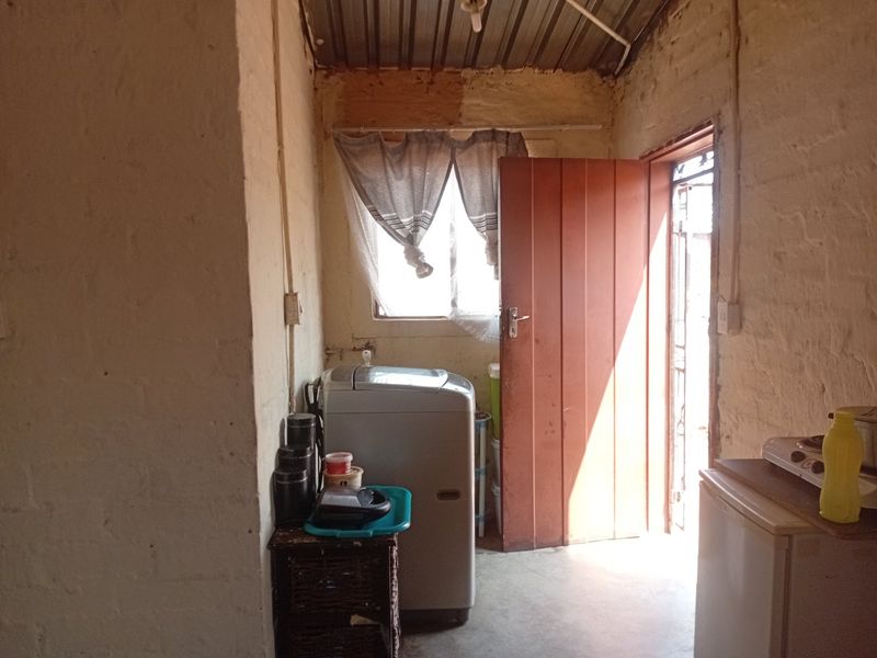 A utility or laundry area featuring exposed brick walls and a corrugated metal ceiling, providing direct access to the exterior.