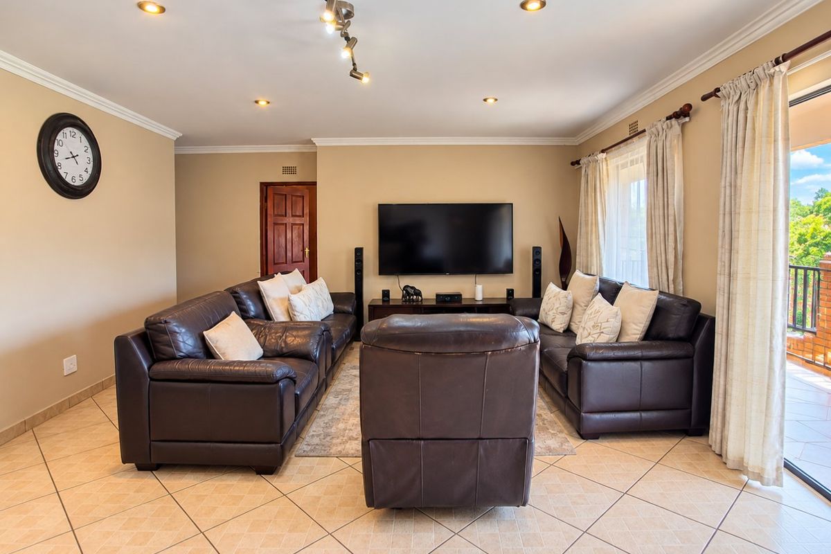 A well-maintained living room featuring tiled flooring, recessed downlighting, and direct access to an outdoor balcony through a sliding glass door.