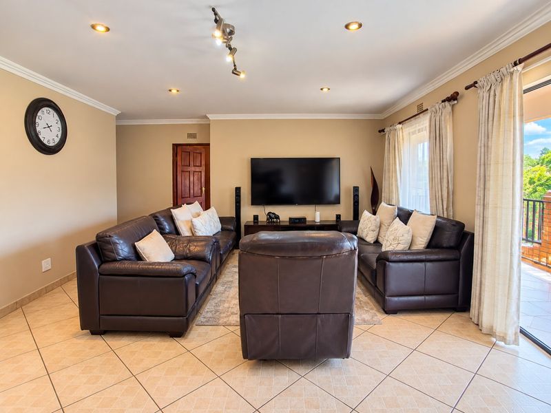 A well-maintained living room featuring tiled flooring, recessed downlighting, and direct access to an outdoor balcony through a sliding glass door.