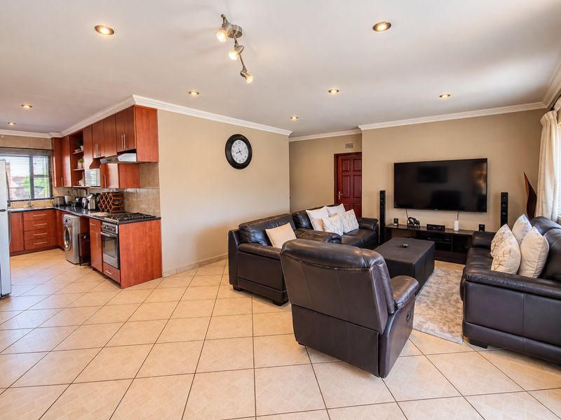 Spacious open-plan living area featuring a well-appointed kitchen with built-in cabinetry, gas hob, and oven, seamlessly flowing into a comfortable lounge space.