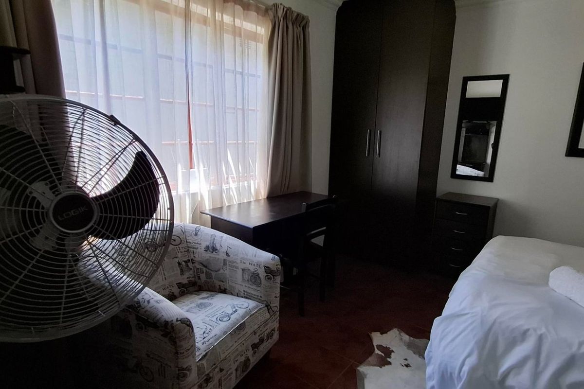 A bedroom featuring tiled flooring and a built-in wardrobe, offering a functional space with natural light from the window.